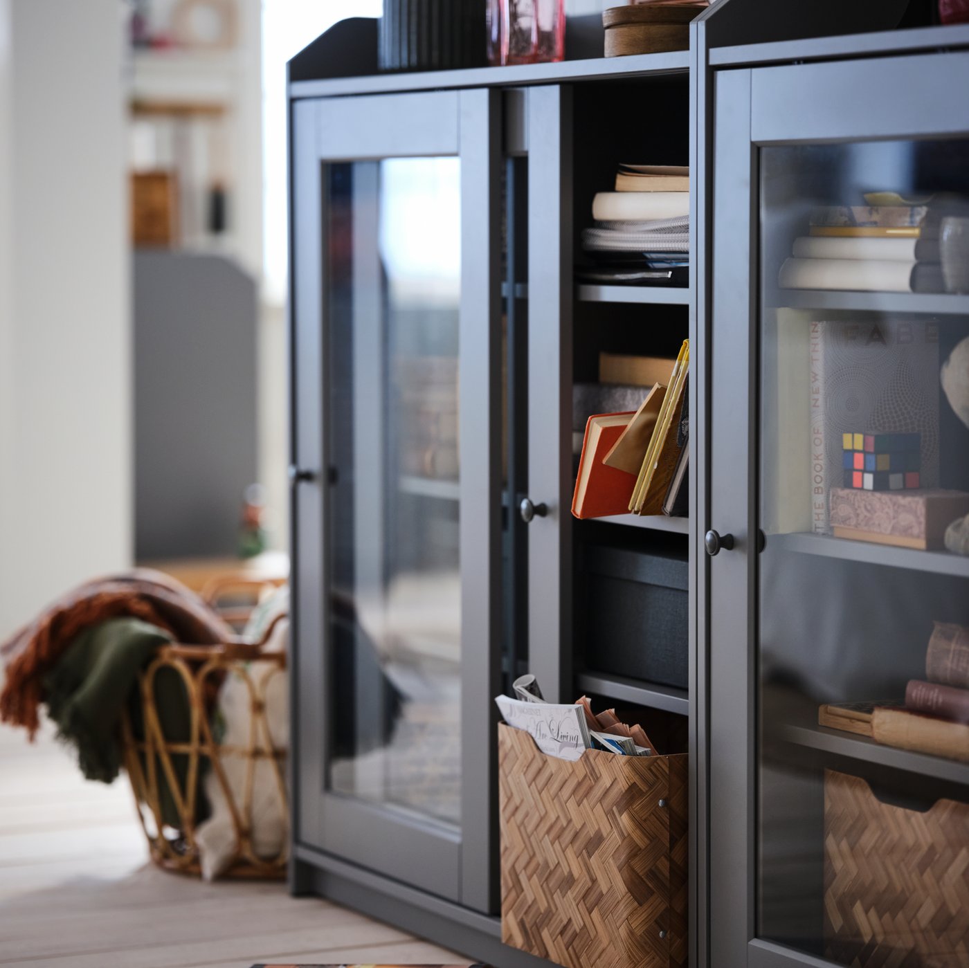 Low dark brown glass sliding door cabinet filled with books and storage baskets