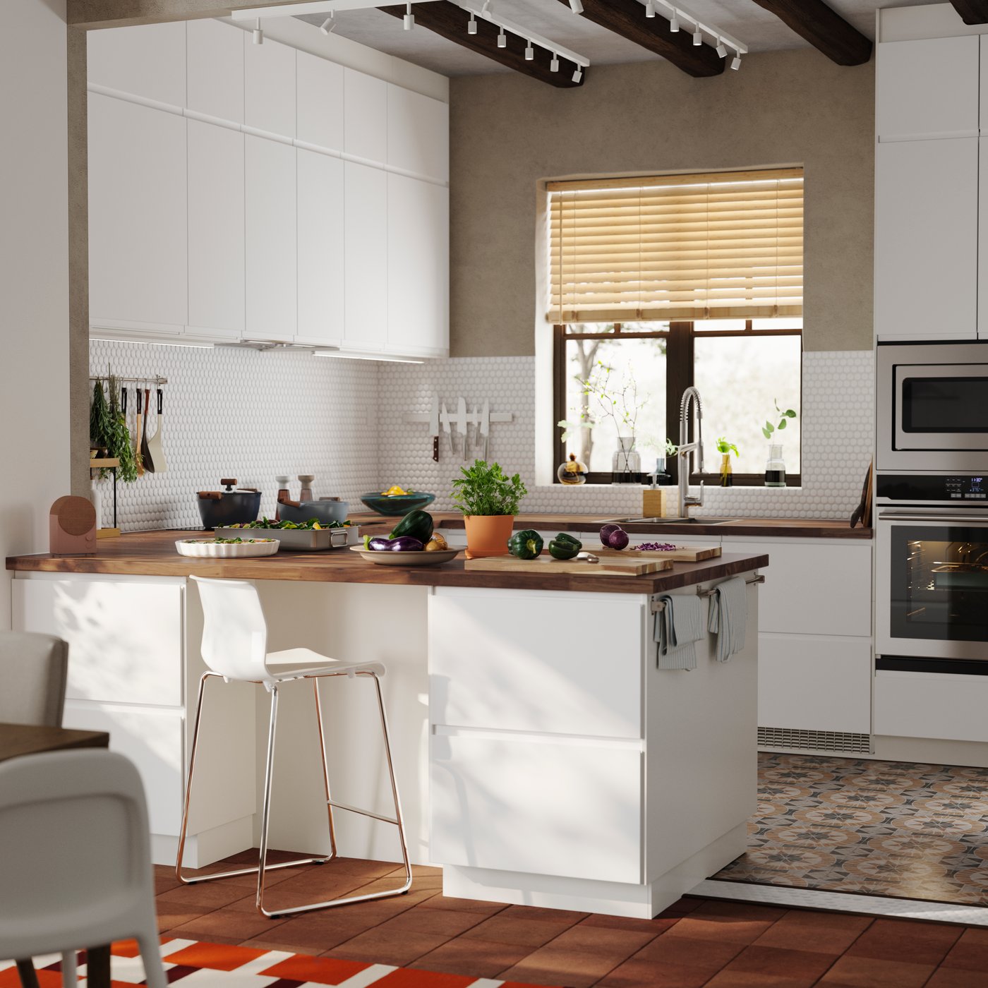 A bright kitchen with a window and matte white VOXTORP fronts has a kitchen peninsula with a bar stool next to it.


