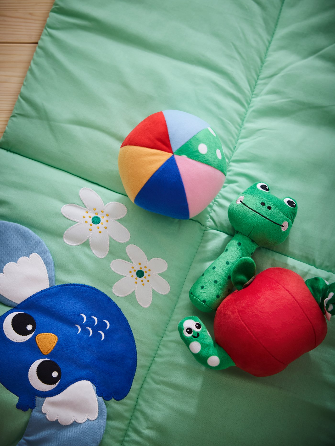 Close-up of colourful SANDBI rattle, soft toy and musical toy on top of SANDBI play mat.