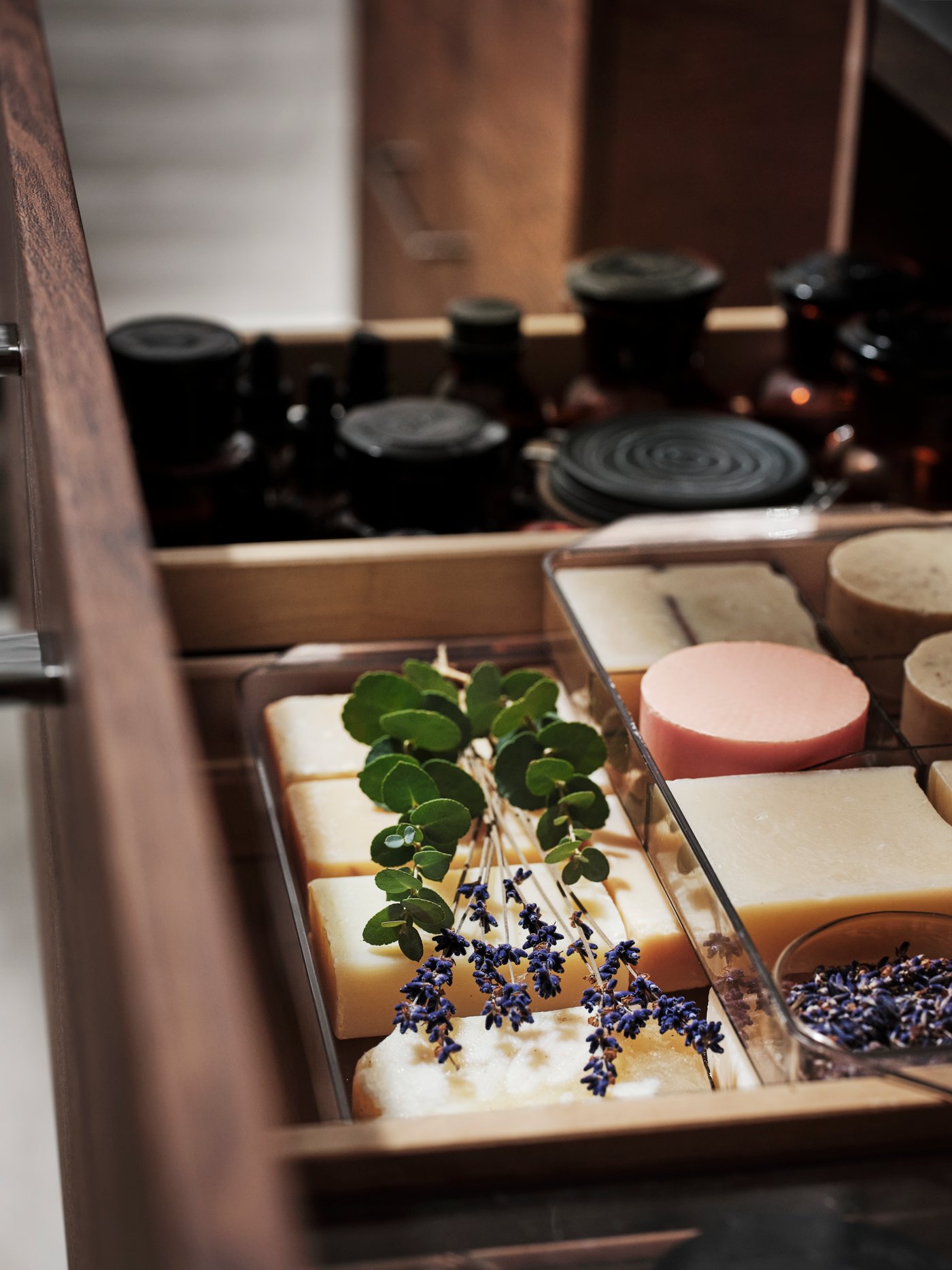 An open drawer of a GODMORGON washstand with storage units holding diverse items like soaps and other toiletries.