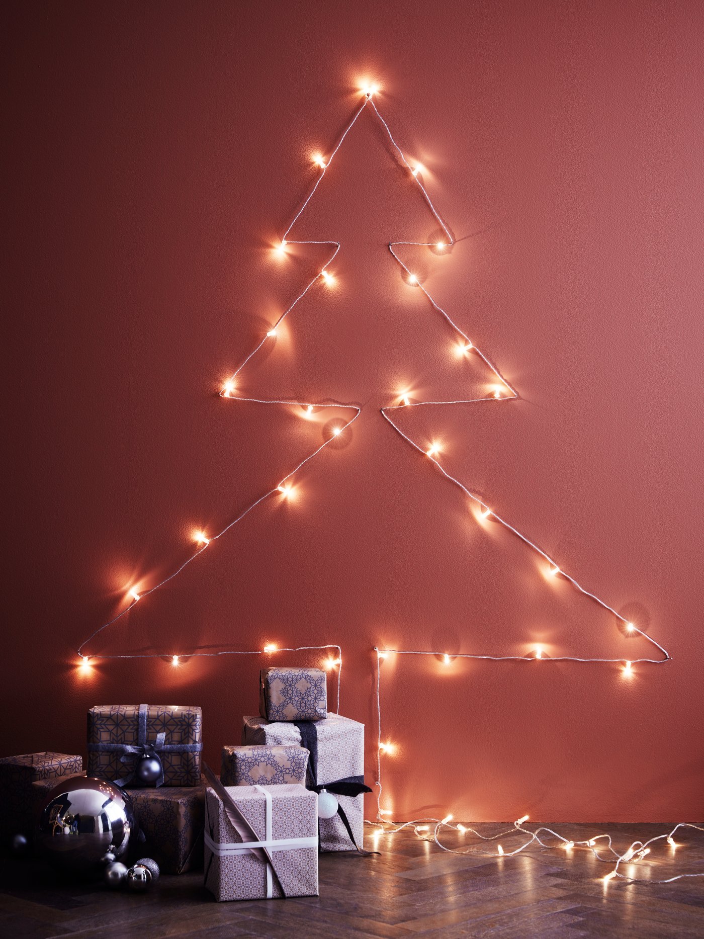 Fixe ta guirlande lumineuse au mur, en forme de sapin de Noël.