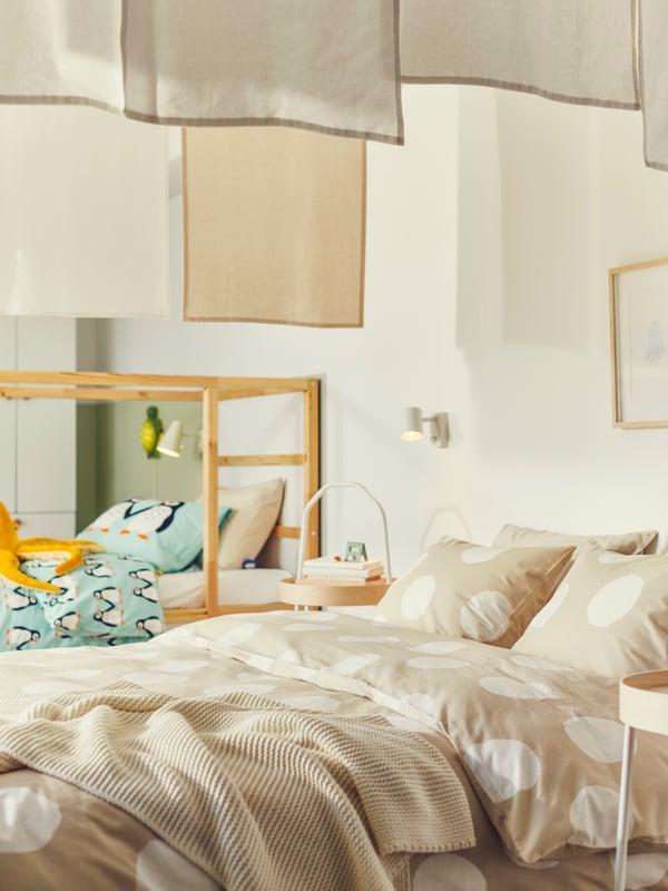 A bedroom with a bed with KLYNNETÅG bed linen with a dotted pattern and a KURA reversible bed with BLÅVINGAD bed linen.