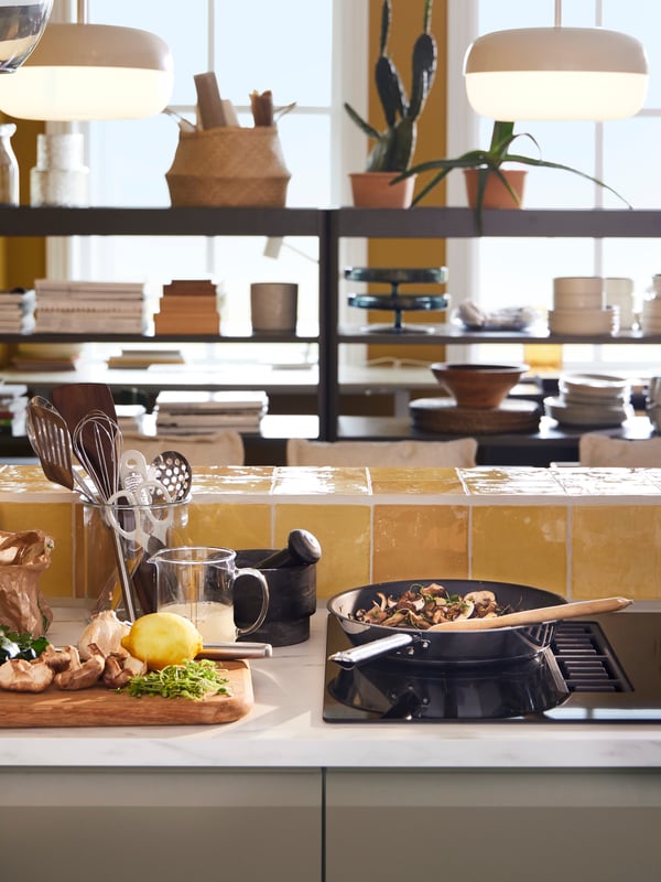 A FÖRDELAKTIG induction hob with integrated extractor and an IKEA 365+ non-stick frying pan on it and BLÅSVERK pendant lamps.