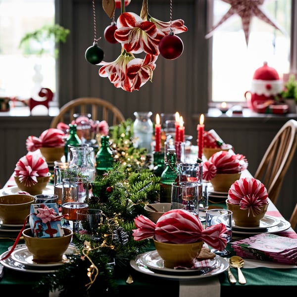 A festively decorated Christmas table is set with VINTERFINT decorations and oversized candy tree ornaments on bowls.