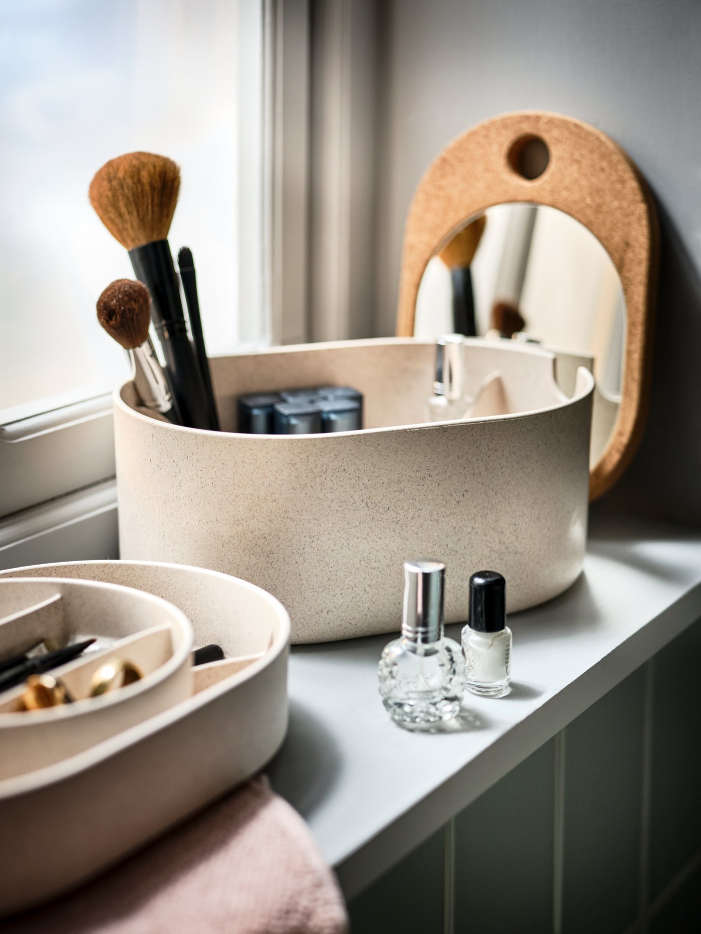 En SAXBORGA makeuo-opbevaring med makeuppensler og neglelak stå i en vindueskarm.