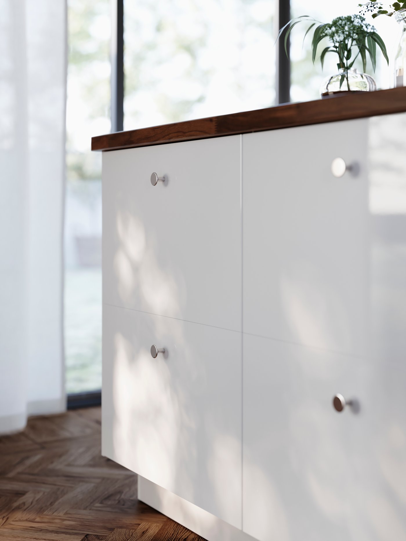 A large kitchen island has four drawers with high-gloss white RINGHULT fronts and KALERUM knobs in a stainless steel colour.