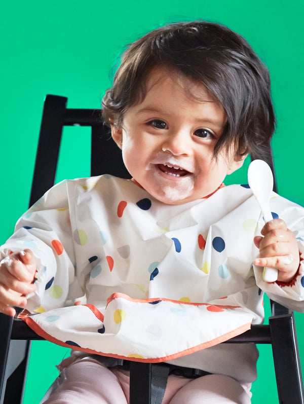 KLADDIG bib on baby boy smiling sitting on AGAM junior chair black
