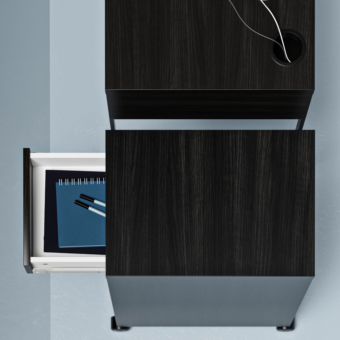 A MICKE drawer unit, its drawer pulled out to reveal notebooks and pens, placed next to a MICKE desk.
