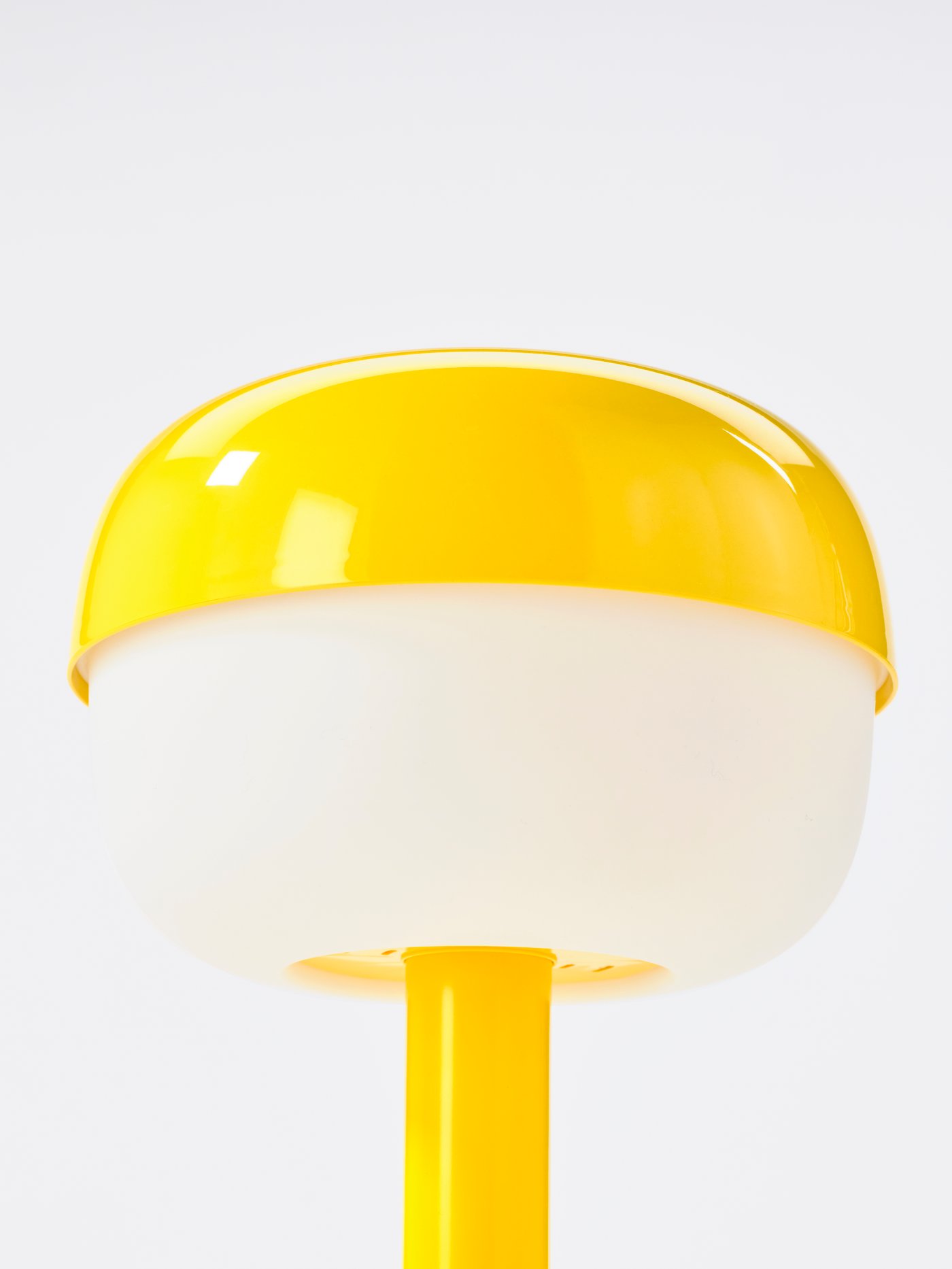 Detailní záběr na žlutou stolní lampu BLÅSVERK, který zobrazuje dvě části stínidla, žlutou a bílou.