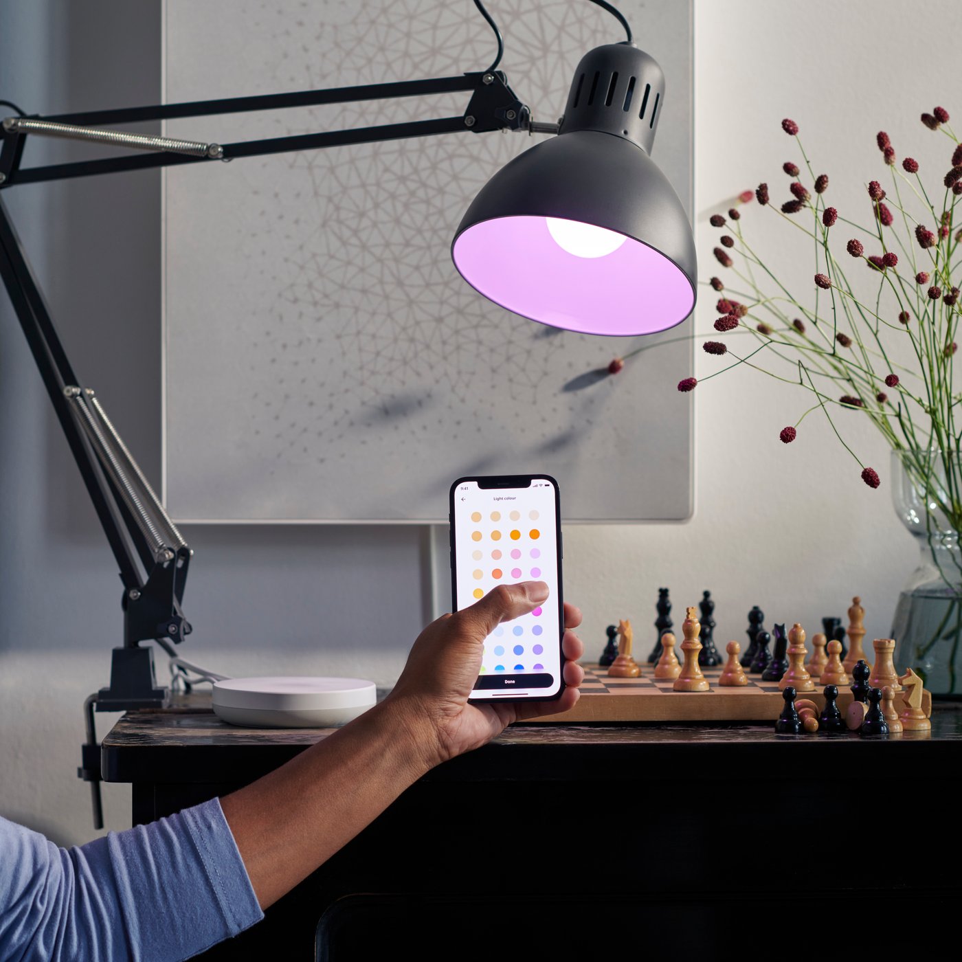 Man hold iPhone with IKEA Hme Smart app on front of TRÅDFRI light bulb