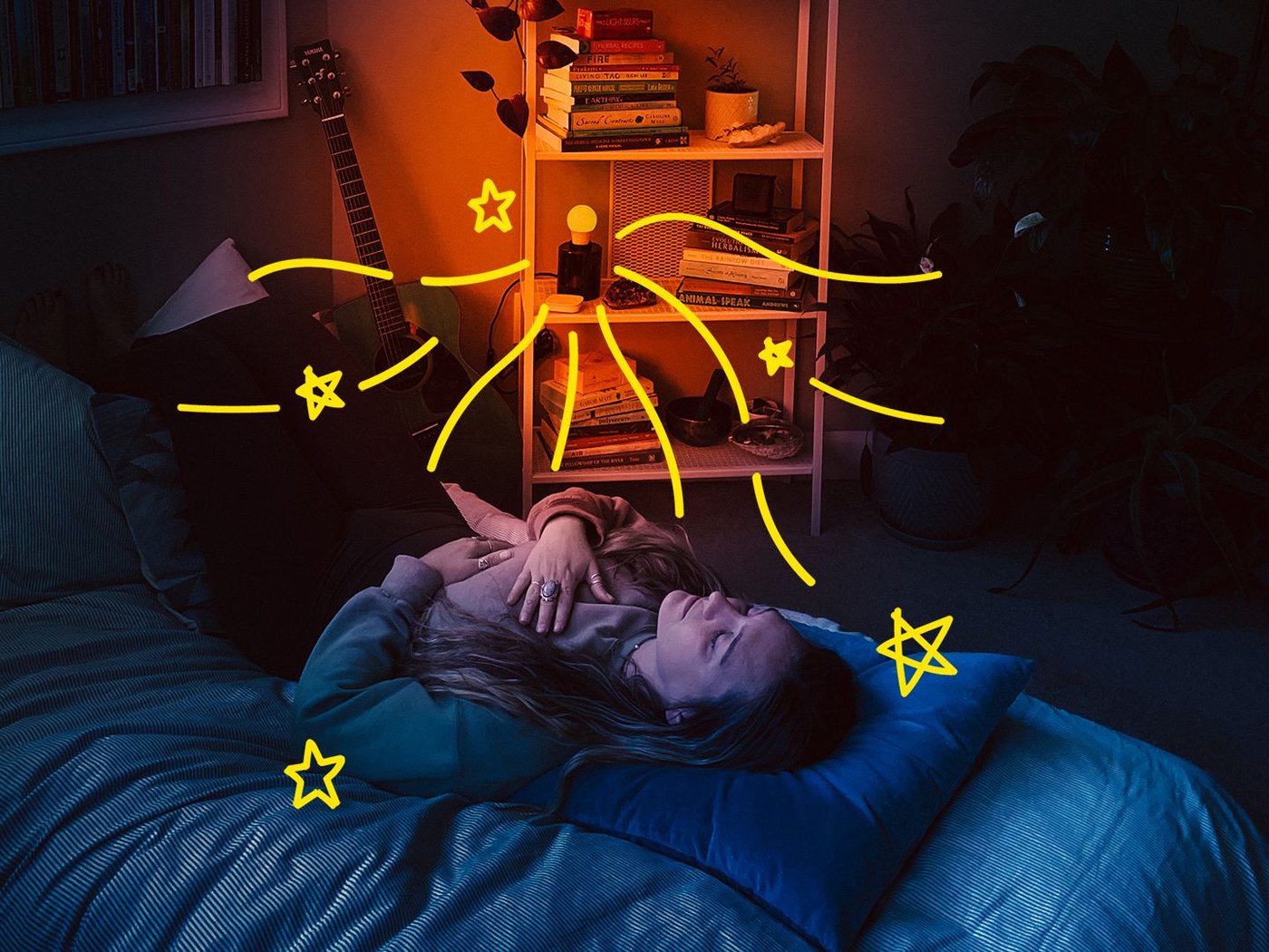 A woman lying on her bed, meditating, in a room illuminated by an orange-coloured light.