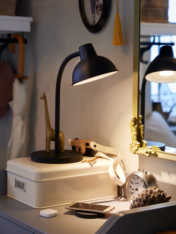 En skrivbordshörna med en tänd lampa och inredningsdetaljer.