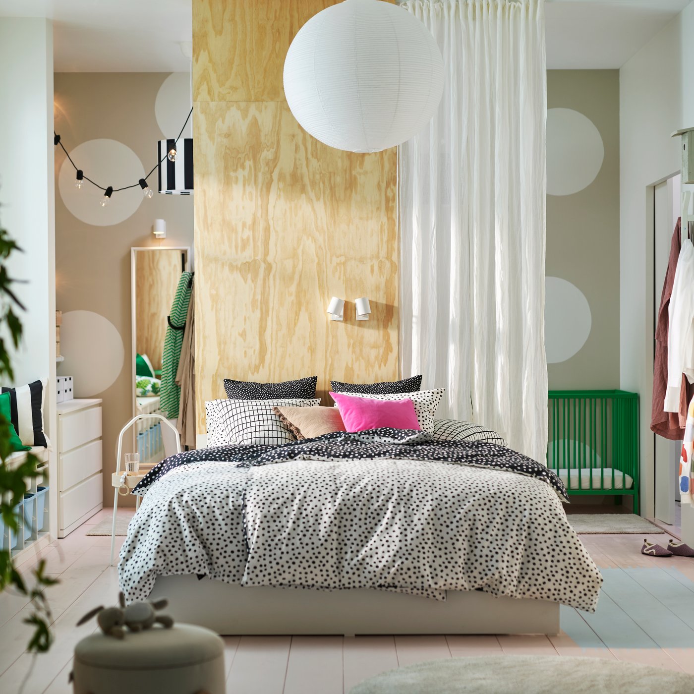 A VIHALS bed with 4 storage boxes covered with black and white BJÖRKGRÅMAL bed linen and bright cushions in a light bedroom.