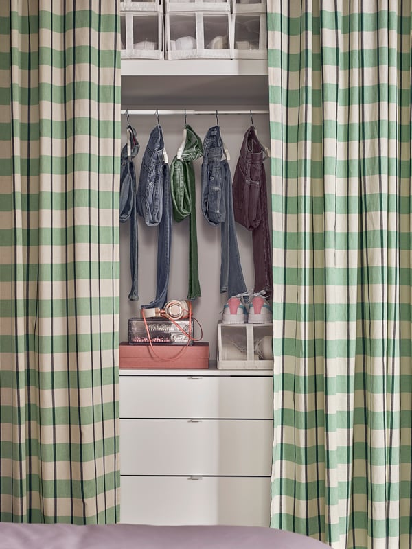 A VIHALS chest with 4 drawers with a hanging rail holding clothing above it and two GLANSHAGSTORN curtains on either side.