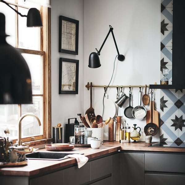 Two SKURUP work/wall lamps are mounted on walls in a corner of a kitchen with dark grey VOXTORP kitchen fronts.