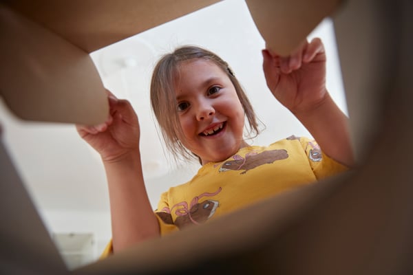 Une jeune fille enthousiaste regarde dans un sac en papier.