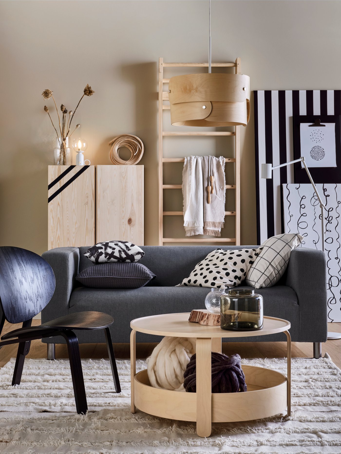 En grå KLIPPAN sofa står i en lys stue med et BORGEBY sofabord, en sort FRÖSET lænestol i forgruden og et IVAR skab og en SÖDÅKRA loftlampe i baggrunden. Passer perfekt til Japandi-stilen.