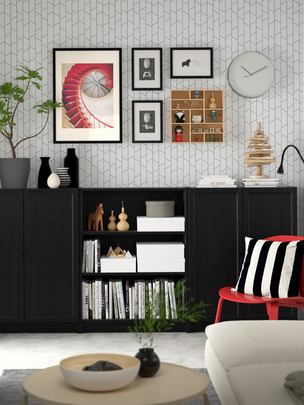 A living room has a series of white BILLY bookcases along one wall, with books and folders neatly organised on the shelves.