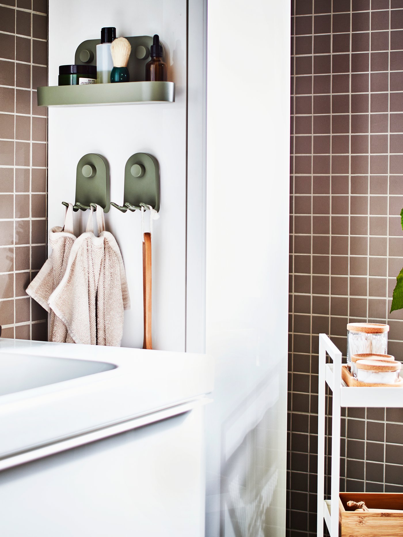 A grey-green ÖBONÄS wall shelf with suction cup