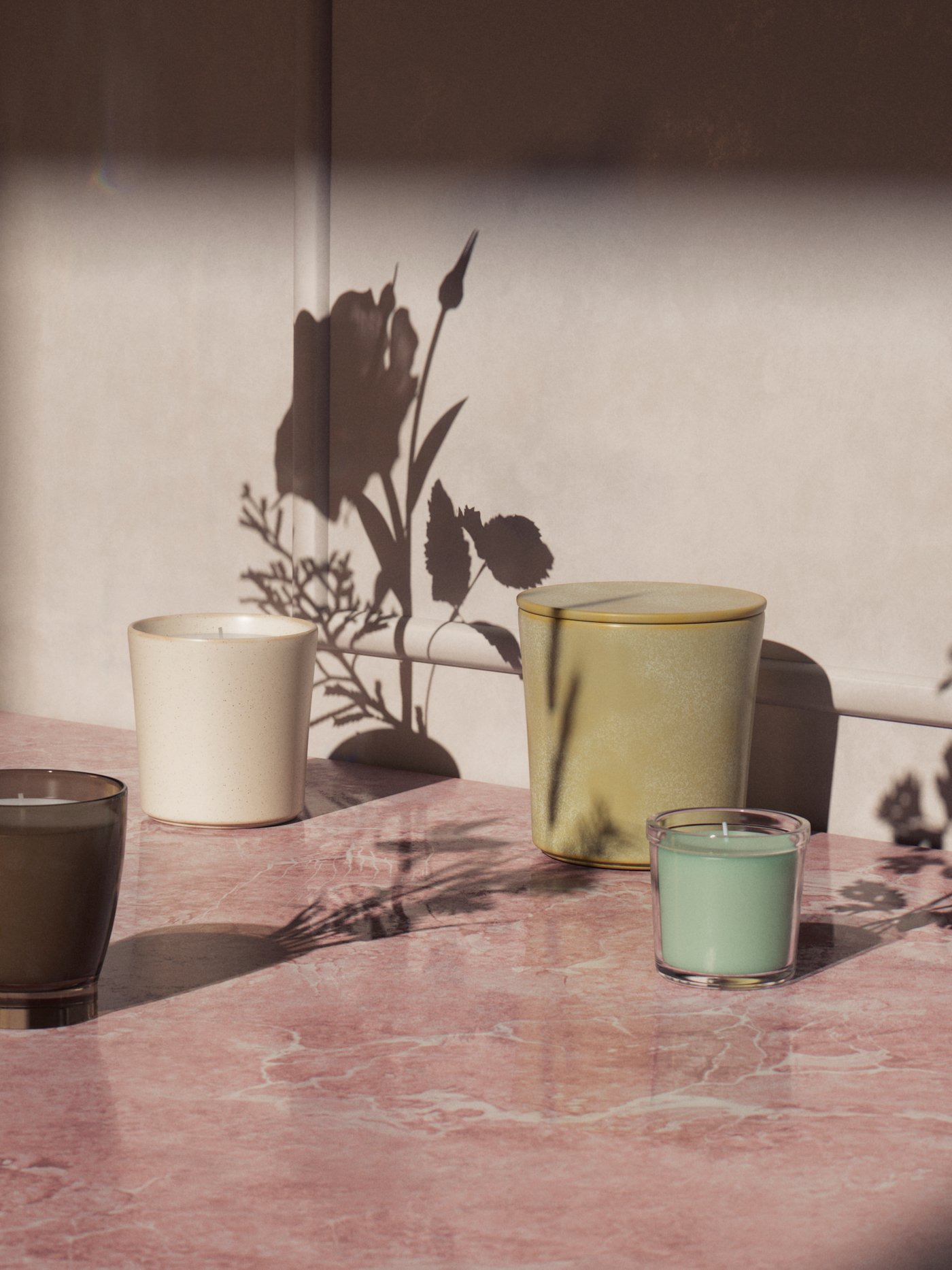 Un iso de cermica color ladrillo, sobre él se ven aceteros de tonos verde muzgo y blanco y un par de velas en vaso de vidrio.
