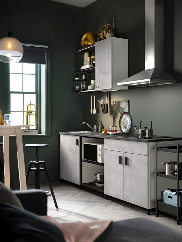 A kitchen with ENHET kitchen cabinets, a RYTMISK wall mounted extractor hood and a JAKOBSBYN pendant lamp hanging from above.