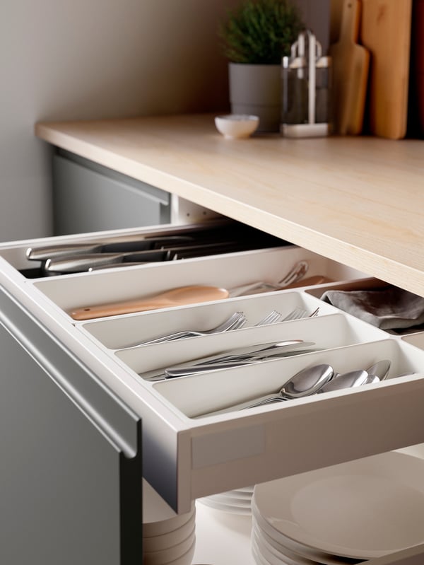 A kitchen drawer with a VOXTORP front opened, revealing cutlery in an UPPDATERA cutlery tray and knives in a knife tray.