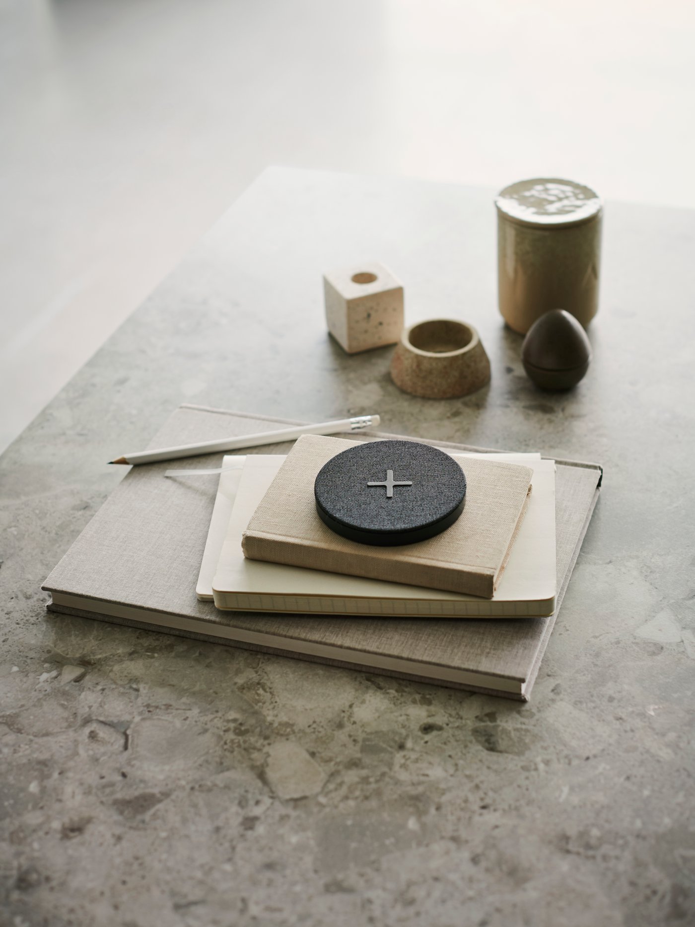 NORDMÄRKE wireless charger sits on a stone worktop with paper notepads. 