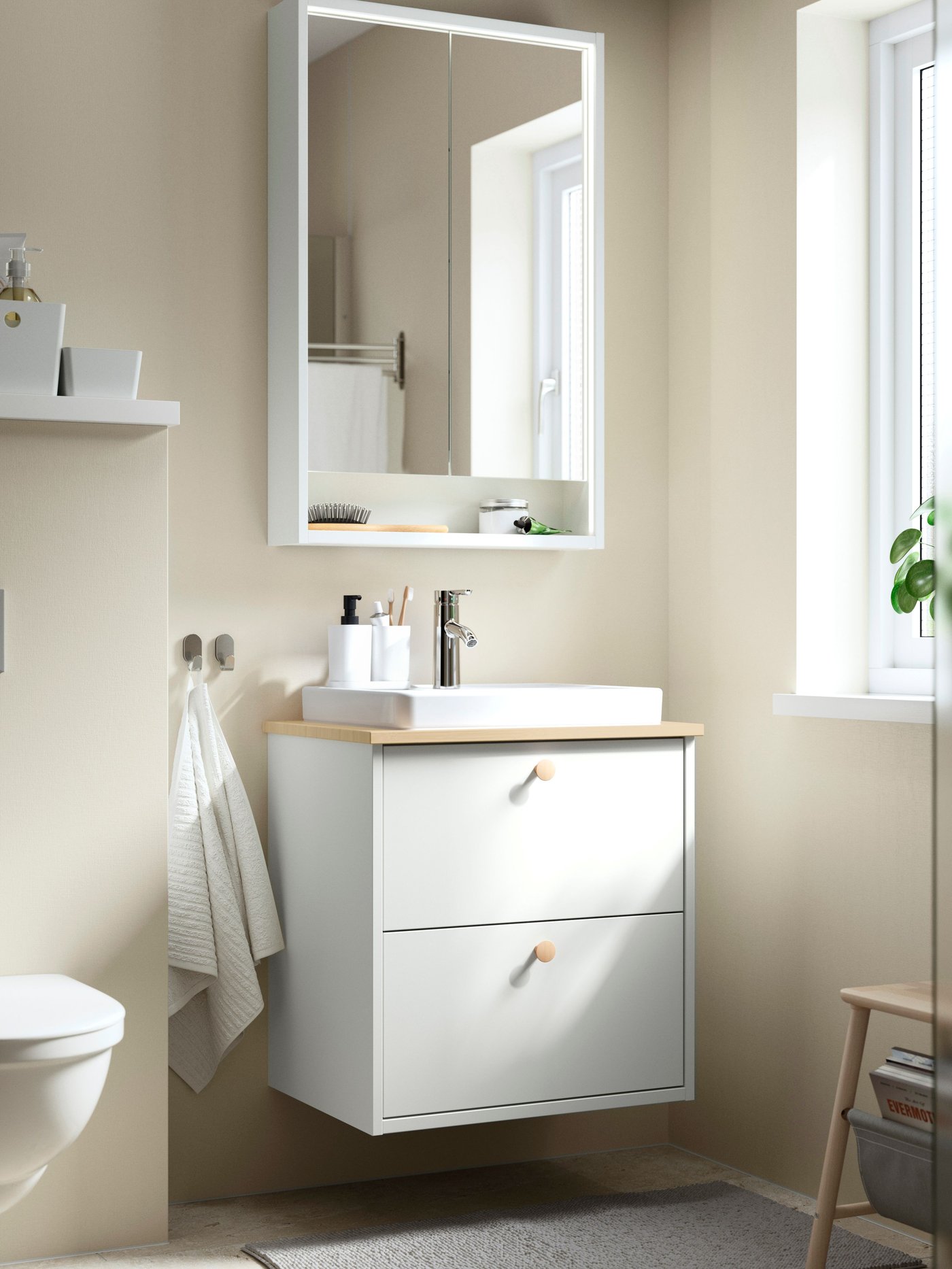 Un bagno con le pareti beige, arredato con un mobile per lavabo HAVBÄCK con cassetti, bianco, un lavabo ORRSJÖN e un mobile a specchio.
