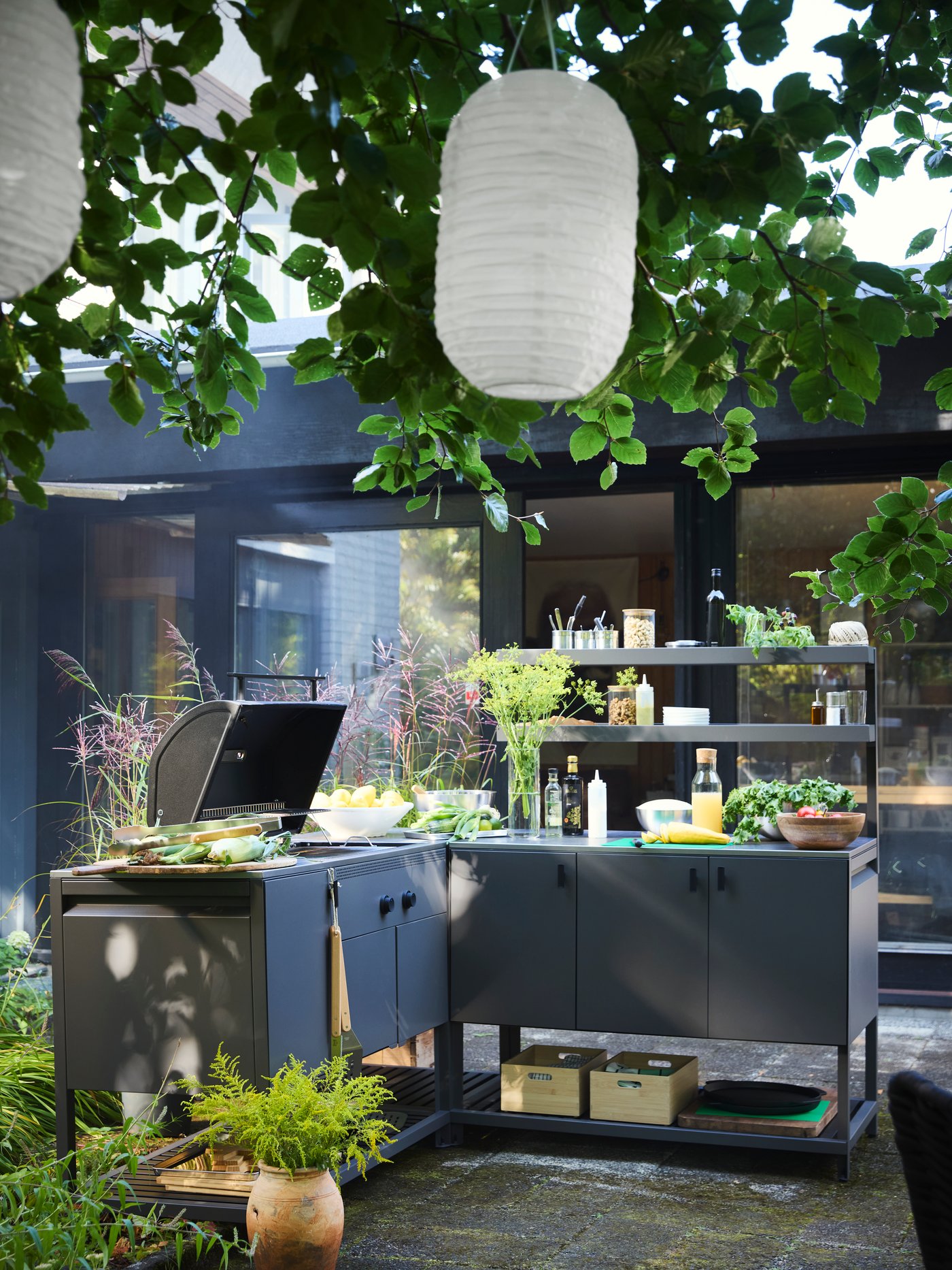 A dark grey BÅTSKÄR outdoor kitchen w charcoal barbecue outside