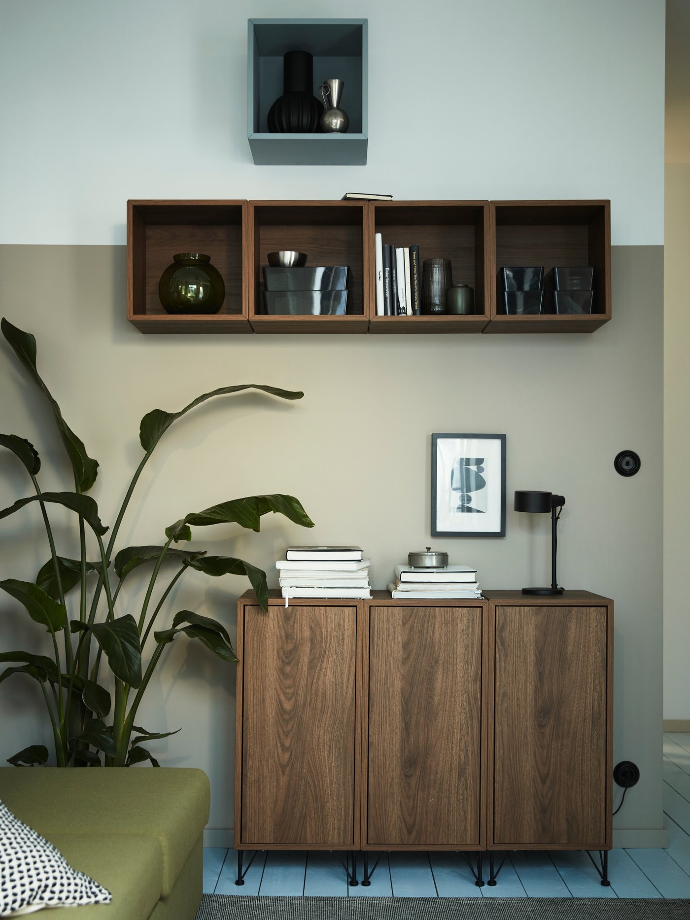 Five EKET wall-mounted shelving units are mounted on a wall above other EKET storage with legs standing on the floor.