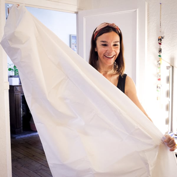 A smiling woman brings out a BJÄRSEN shower curtain.