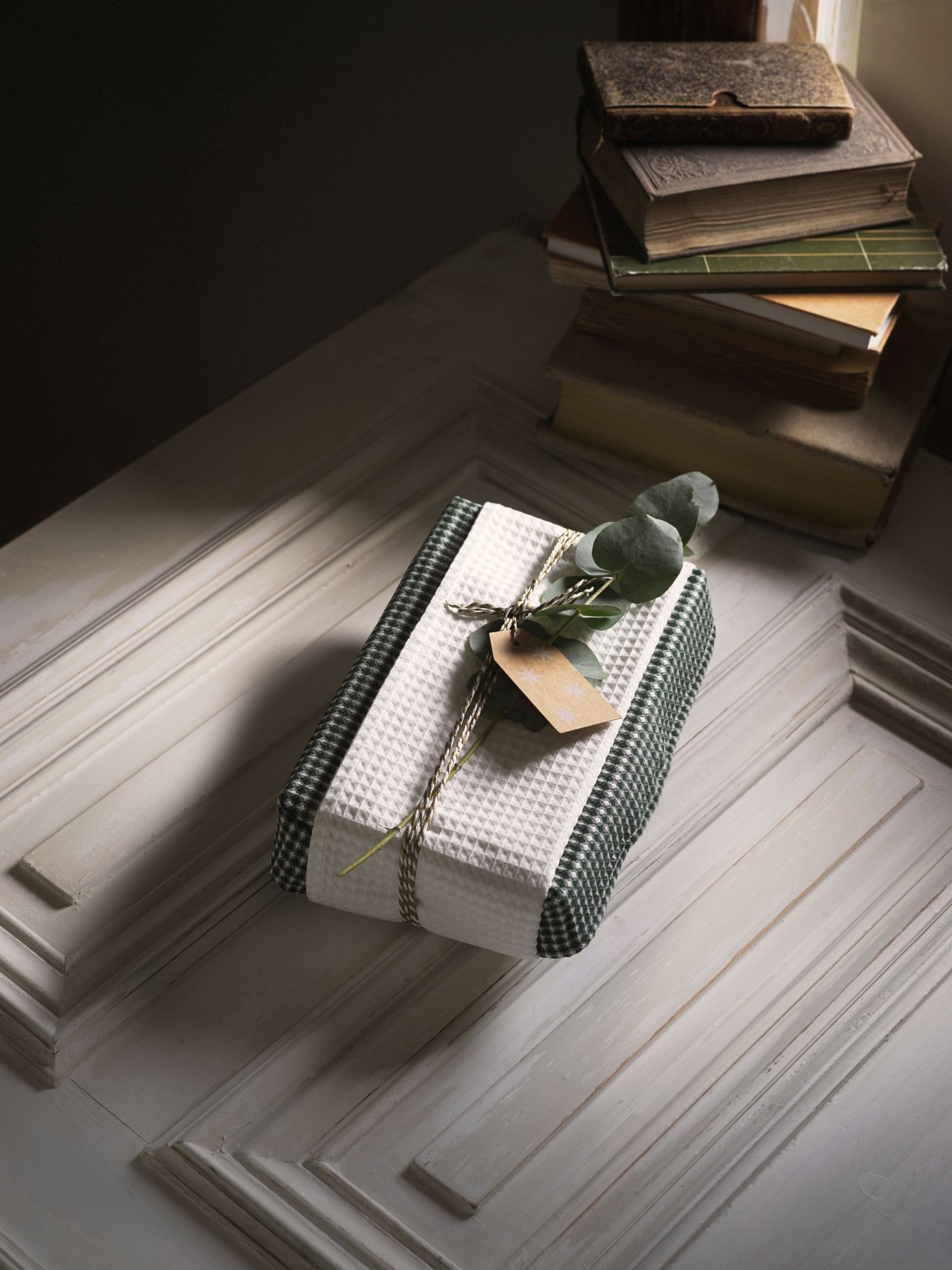 R: A stack of books, a wrapped gift, and a cup of coffee on a wooden table, labeled “Remember to surprise him with a gift”