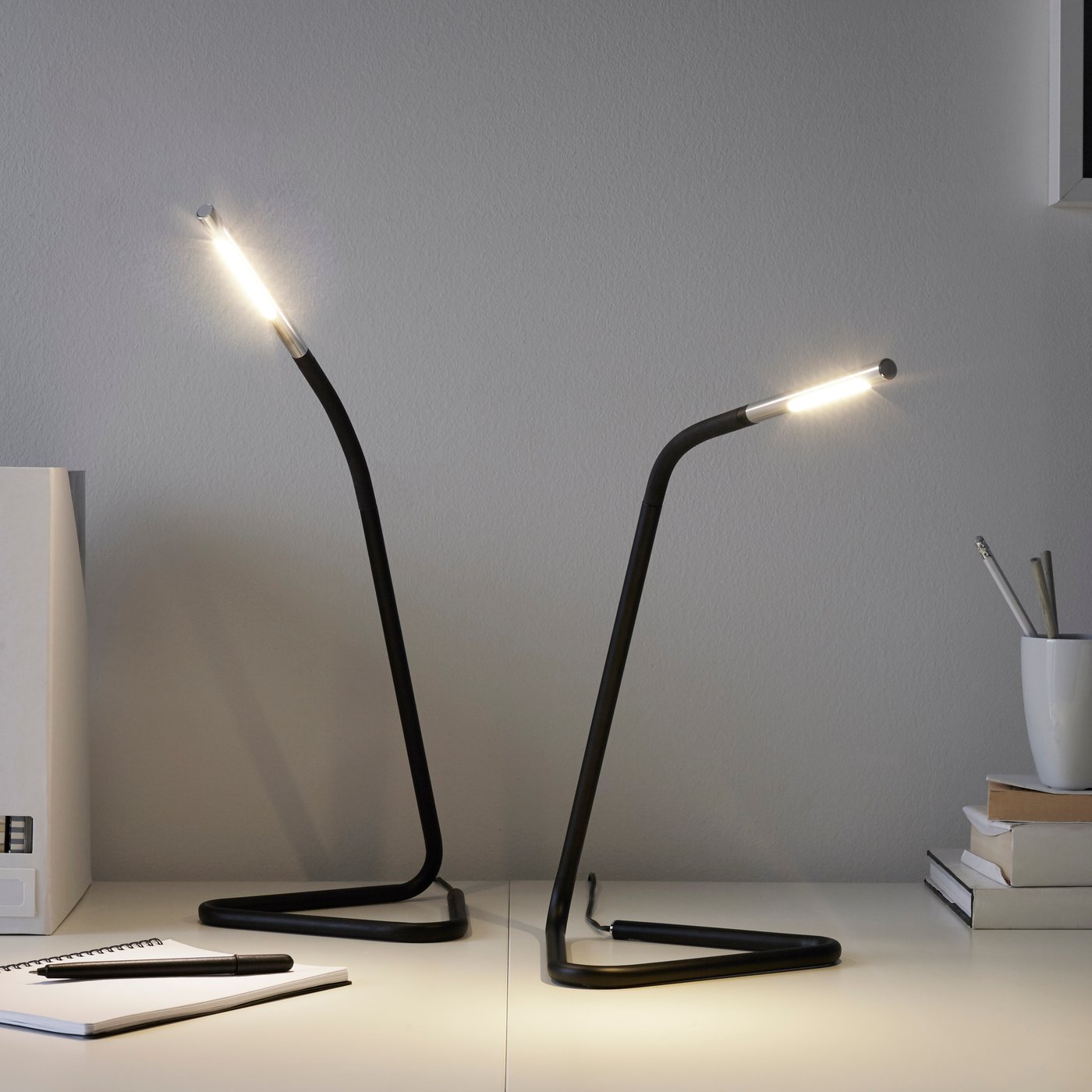 Two black desk lamps on a table