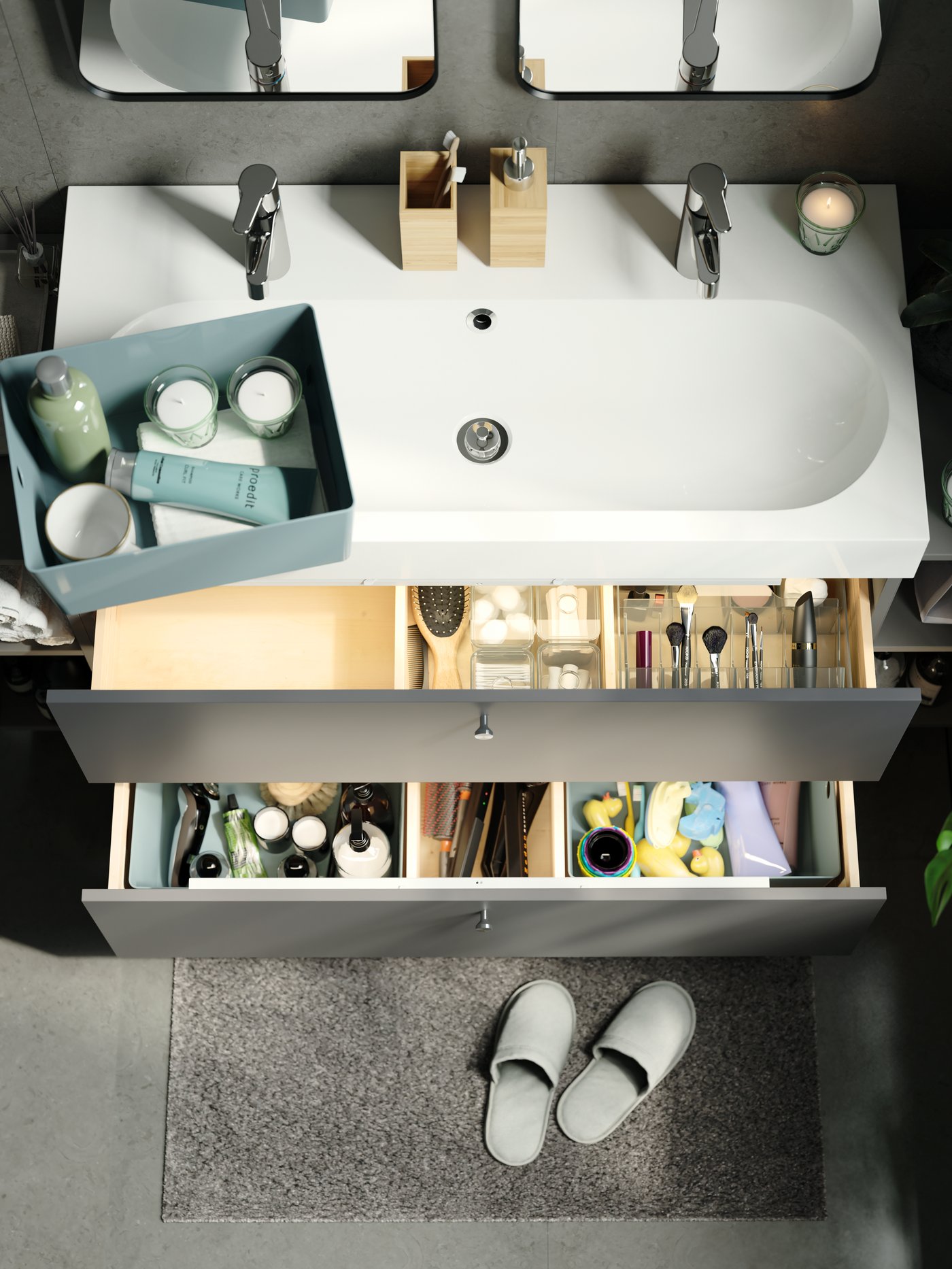Open drawers of a washstand containing a smoked GODMORGON box with compartments and green storage boxes with toiletries.