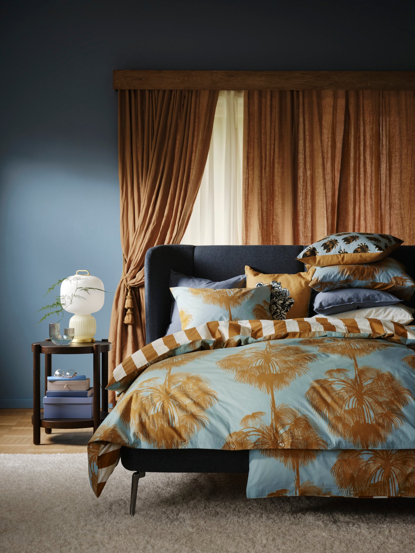 Schlafzimmer mit Vorhängen in der Farbe Sundial und einem dunkelgrauen Bett mit ÄNGLATRUMPET-Bettwäsche.