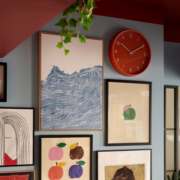 A brightly coloured room with a wall section filled with neatly arranged framed art and an orange BONDIS clock.