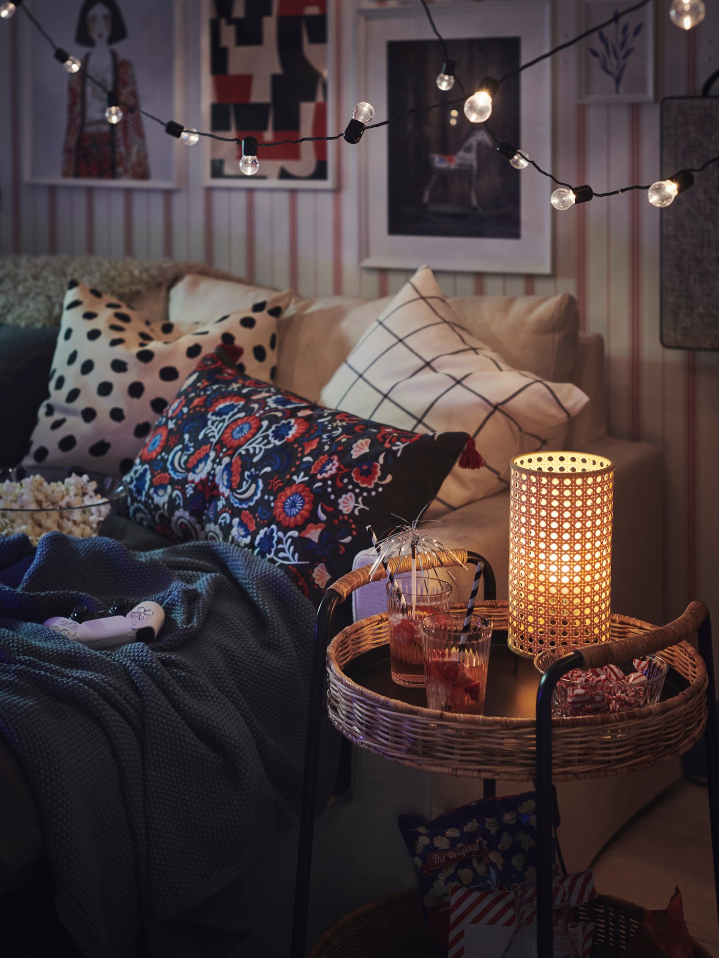 Ein Wohnzimmer mit einem Sofa mit vielen Kissen, gedimmter Bleuchtung und Popcorn.