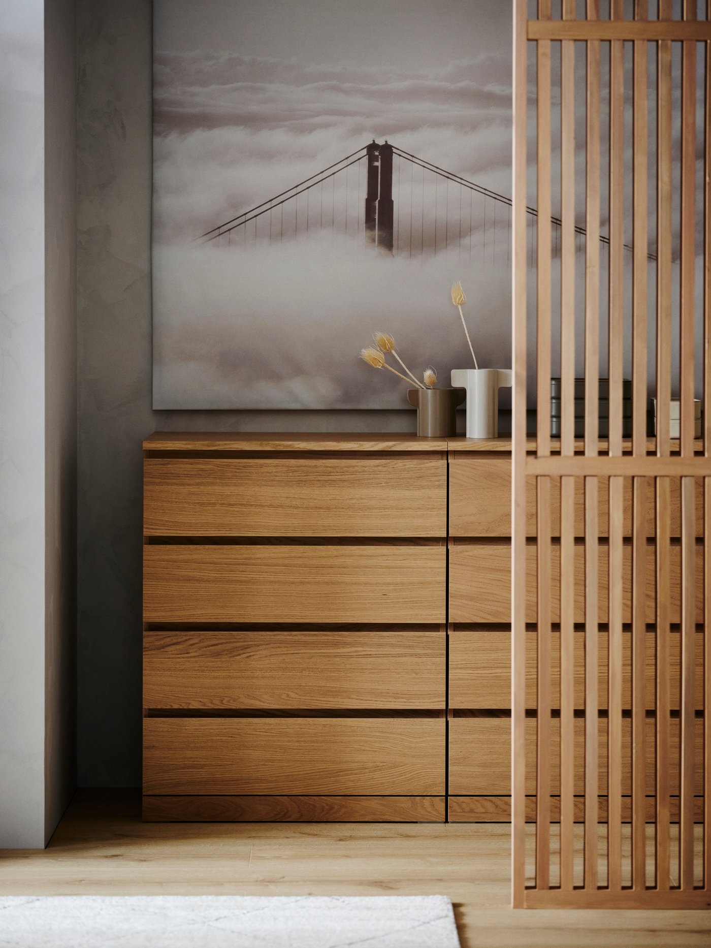 Two white stained oak veneer MALM chests with 4 drawers side by side with a large picture behind it and a beige rug in front.