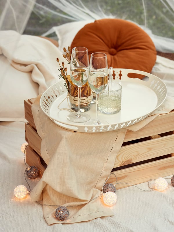 En bakke med glas står på en trækasse på et tæppe.