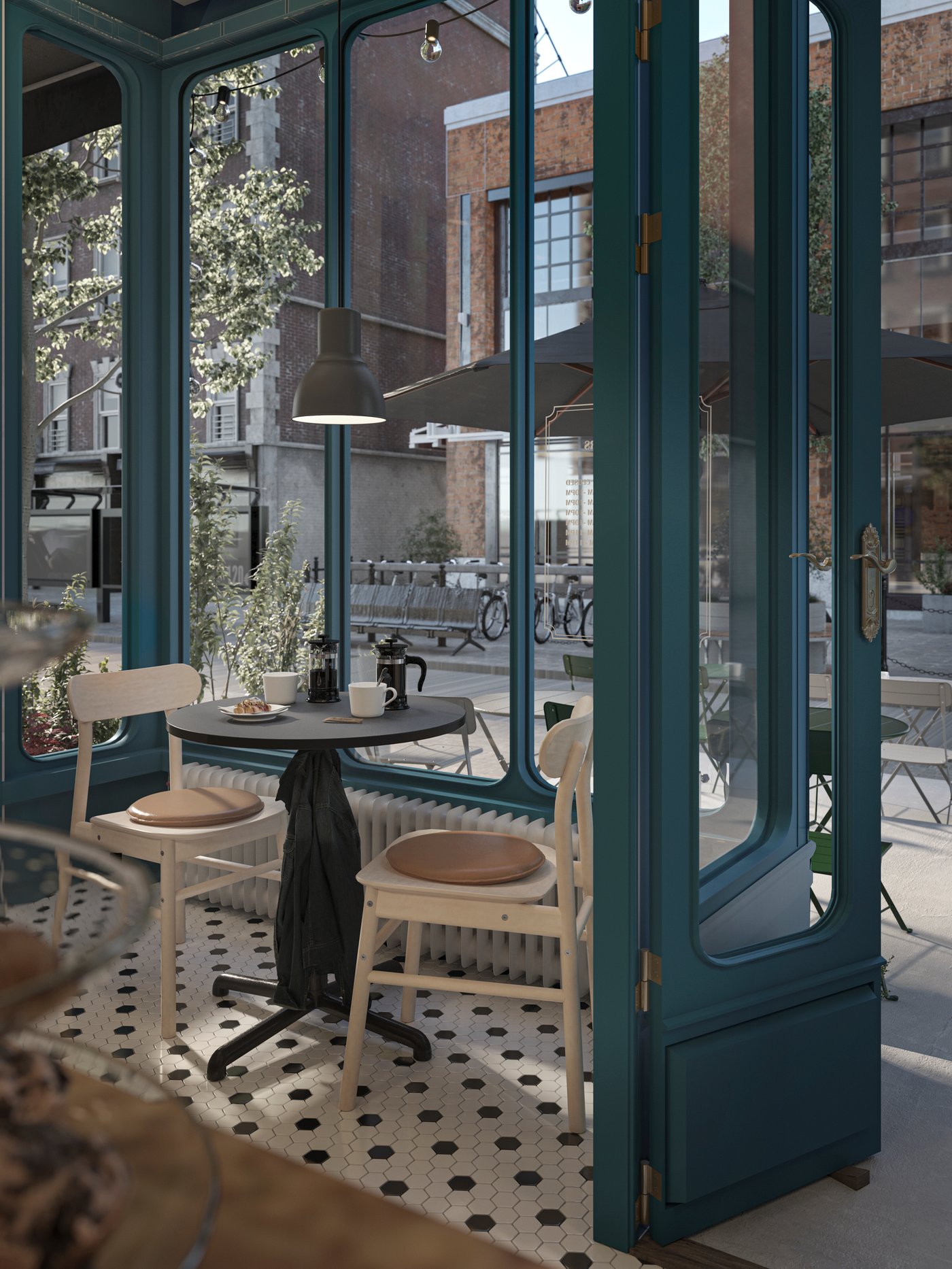 A STENSELE table holding coffee makers and cups with two RÖNNINGE birch chairs around it, by a window inside a café.