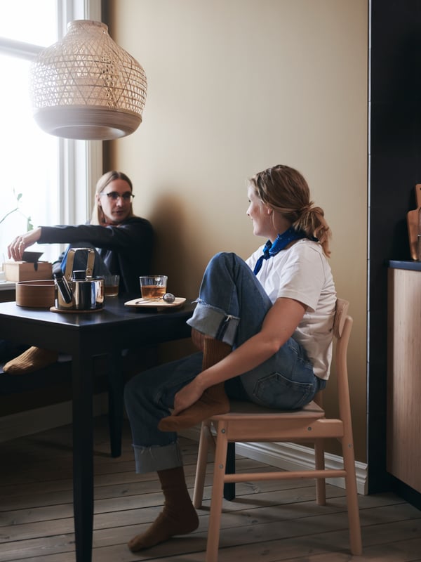 A couple enjoy a quiet tea break at their LERHAMN table, with a MISTERHULT pendant lamp hanging overhead.