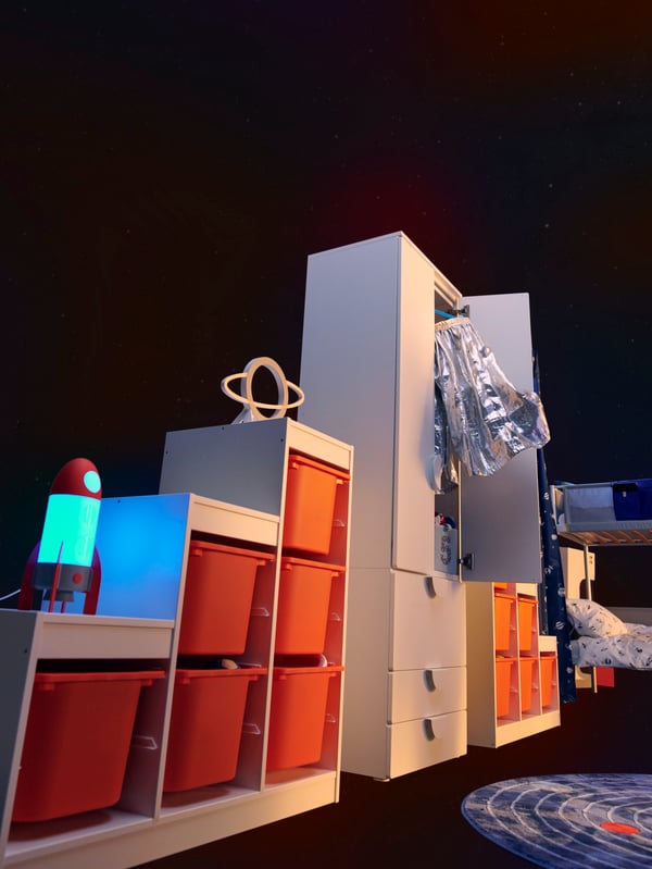 引き出しが3個付いたホワイトのSMÅSTAD/スモースタード&PLATSA/プラッツァ ワードローブの両側に、ホワイトのTROFAST/トロファスト フレームが2個あり、オレンジの収納ボックスが入っている。