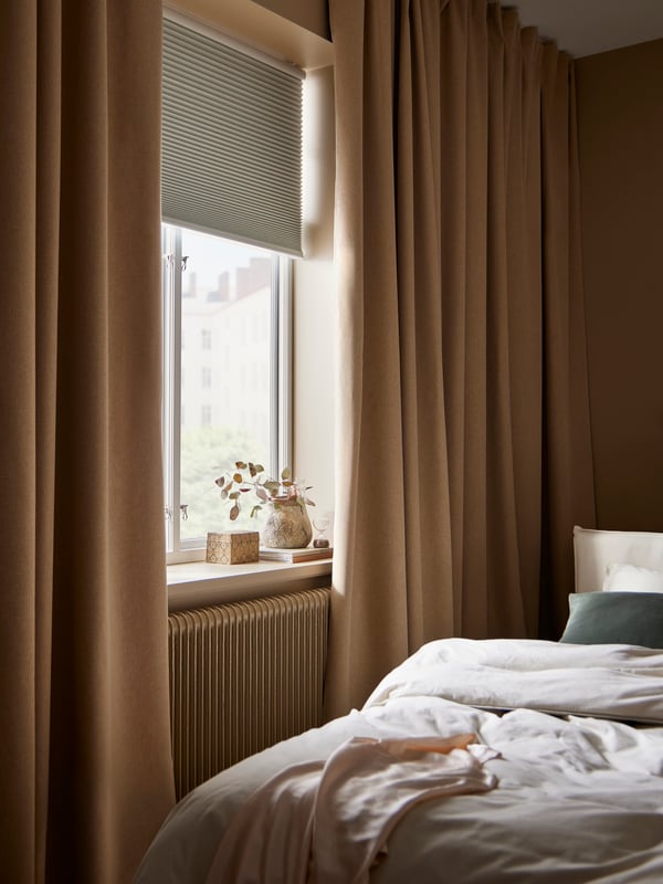 ROSENMANDEL room darkening curtains hang in front of a bedroom window with a white TREDANSEN block-out cellular blind on it.