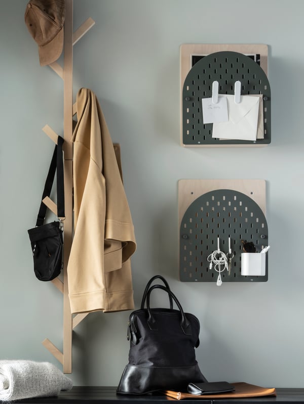 Part of a hallway with two VATTENKAR wall storage units next to two birch TJUSIG vertical hook racks, garments hung on them.