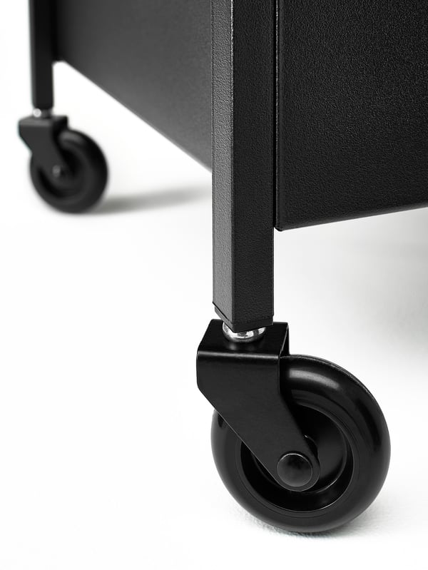 A close-up of two wheels belonging to a NISSAFORS trolley in black. The trolley is in a white studio space.