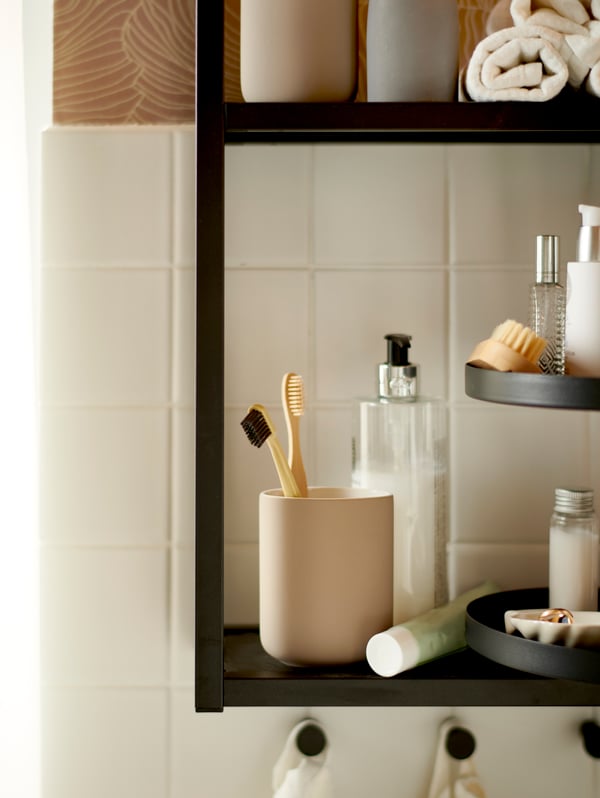A tan EKLON toothbrush holder sitting on a black bathroom shelf.