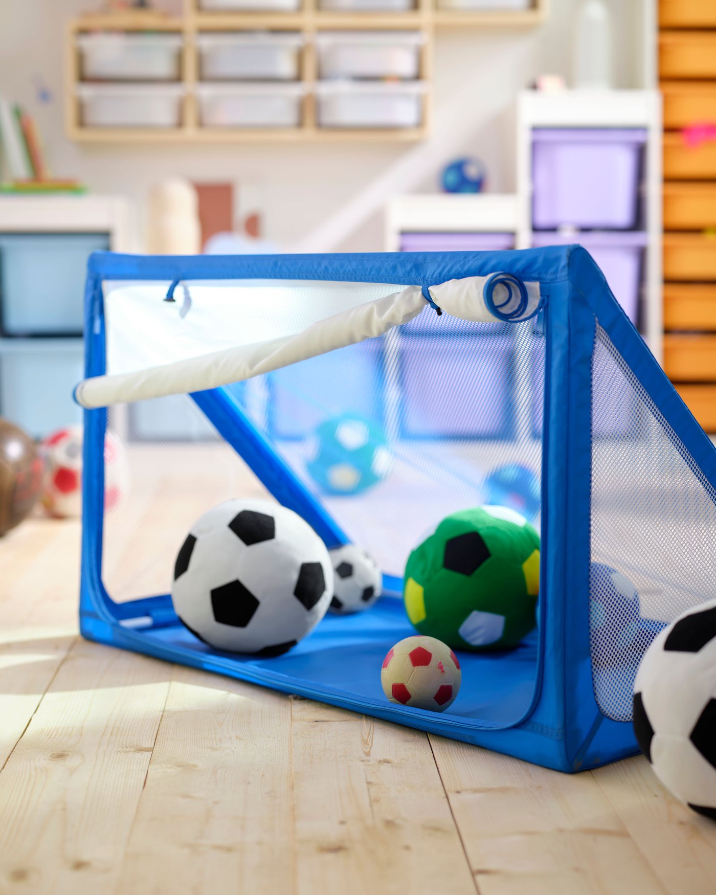 Una portería con almacenamiento SPORTSLIG azul, llena de pelotas de fútbol de peluche SPARKA.