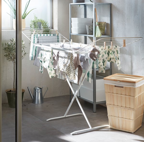 A full clothes rack in a laundry room with a laundry basket next to it