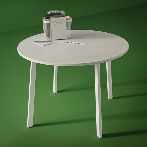 A basket containing magazines is sitting on a white and round MITTZON conference table in a green room.