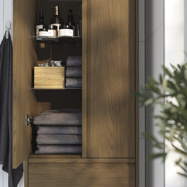 Wooden bathroom cabinet with shelves and drawers. Stores towels and toiletries. Integrated handles for modern look.